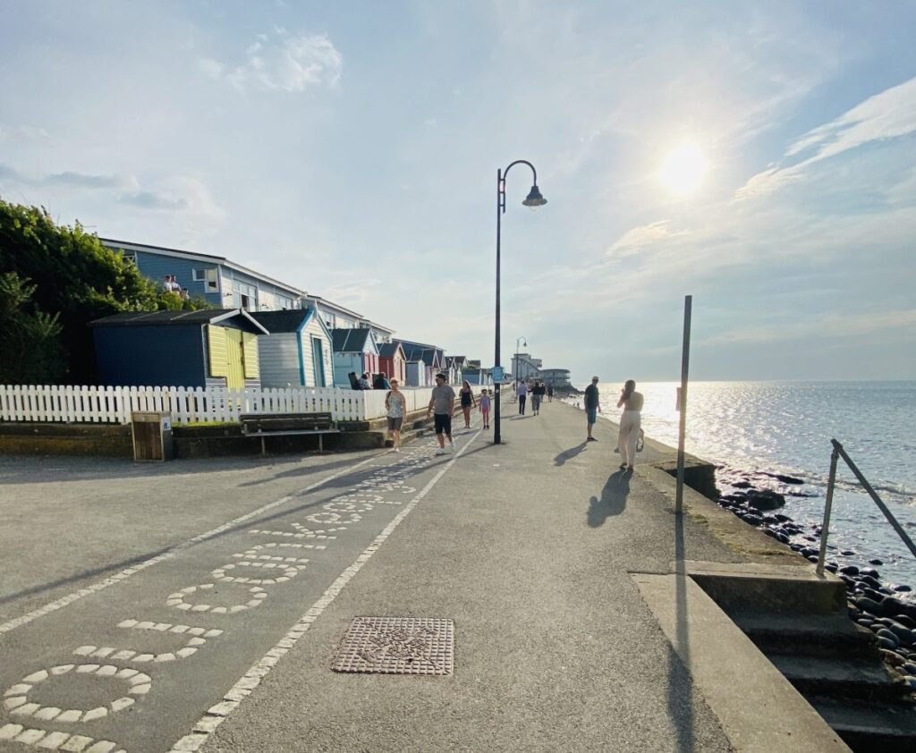 image of the promenade at westward ho. there are a number of colourful beach huts that sit opposite the ocean